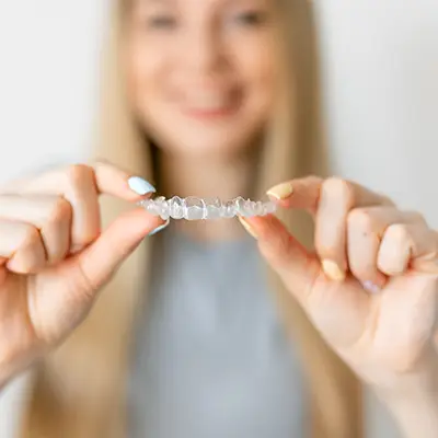 A woman holding invisalign in both her hands, to show how invisible they can be.