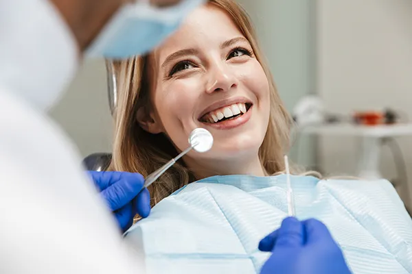 A female patient happily waiting in a dental chair for her dentist to begin her routine dental exam